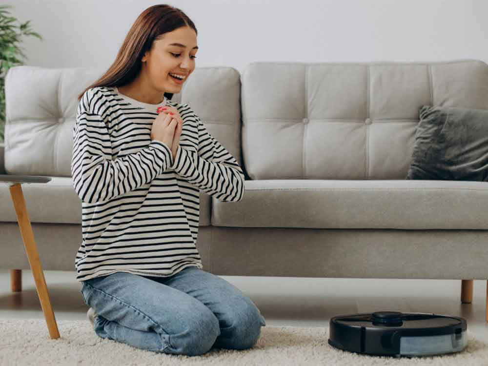 Robot Süpürgenizi İlk Günkü Gibi Kullanın: Temizlik Rehberi 1 robot süpürgesinin başında duran mutlu bir kadın